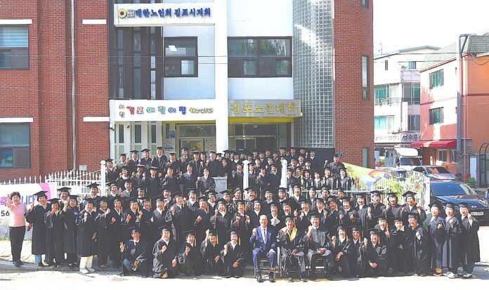 김포노인대학 4학년 졸업생들이 노인대학 건물 앞에서 졸업 기념 사진 촬영을 하고 있다.